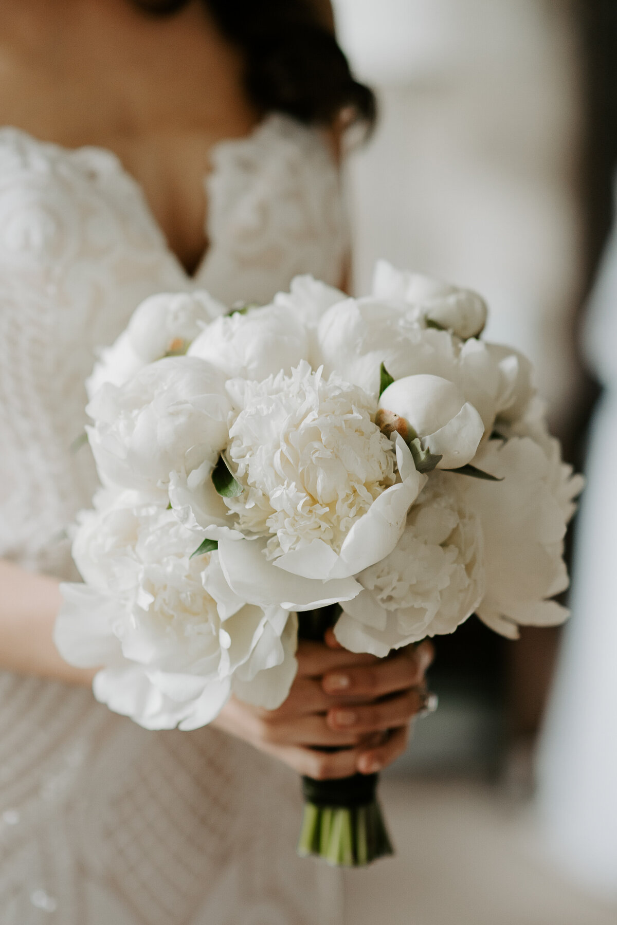 A bride holding a bouquet of lush white peonies at a Montreal wedding.