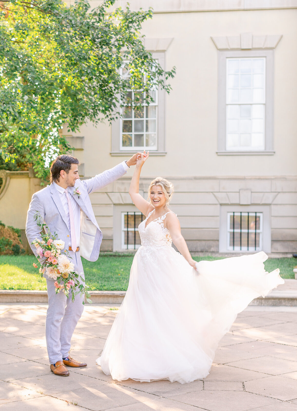 Groom twirling bride in front of Great Marsh Estate in Bealeton, Virginia in the summer. Captured by Bethany Aubre Photography.