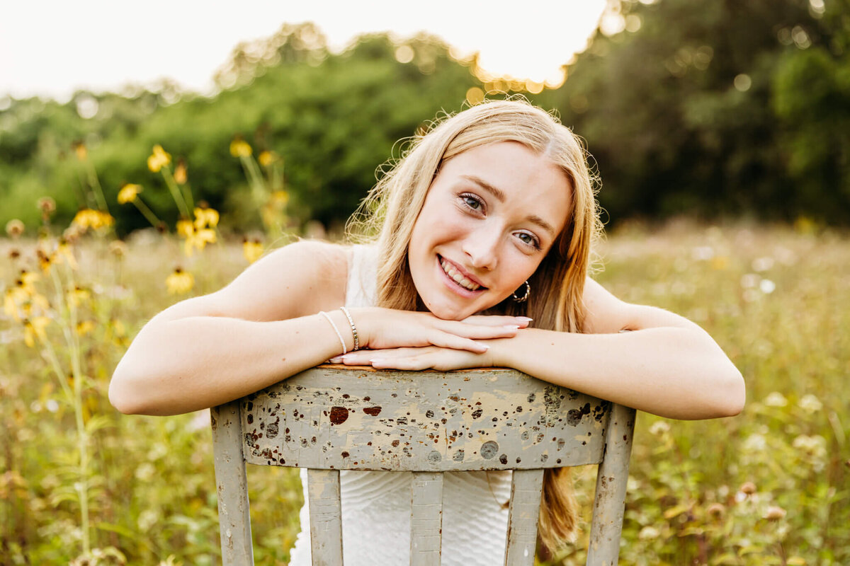 gorgeous Appleton high school senior sitting backwards on a chair and resting her chin on her hands captured by Ashley Kalbus