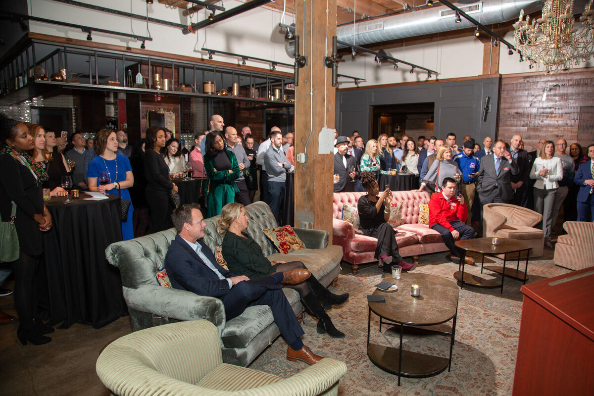 Large group of people standing and sitting listening