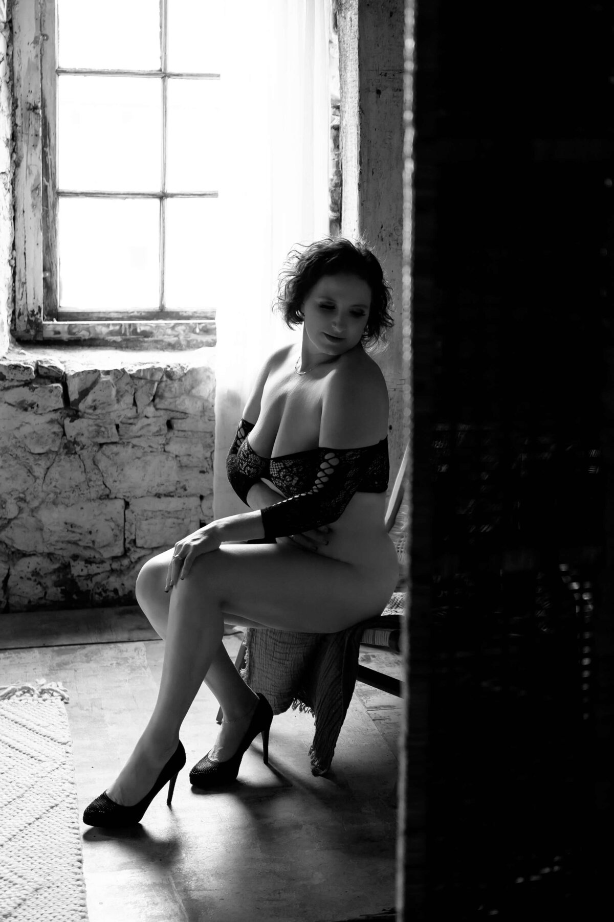black and white photo of a woman sitting on a chair wearing black lingerie 