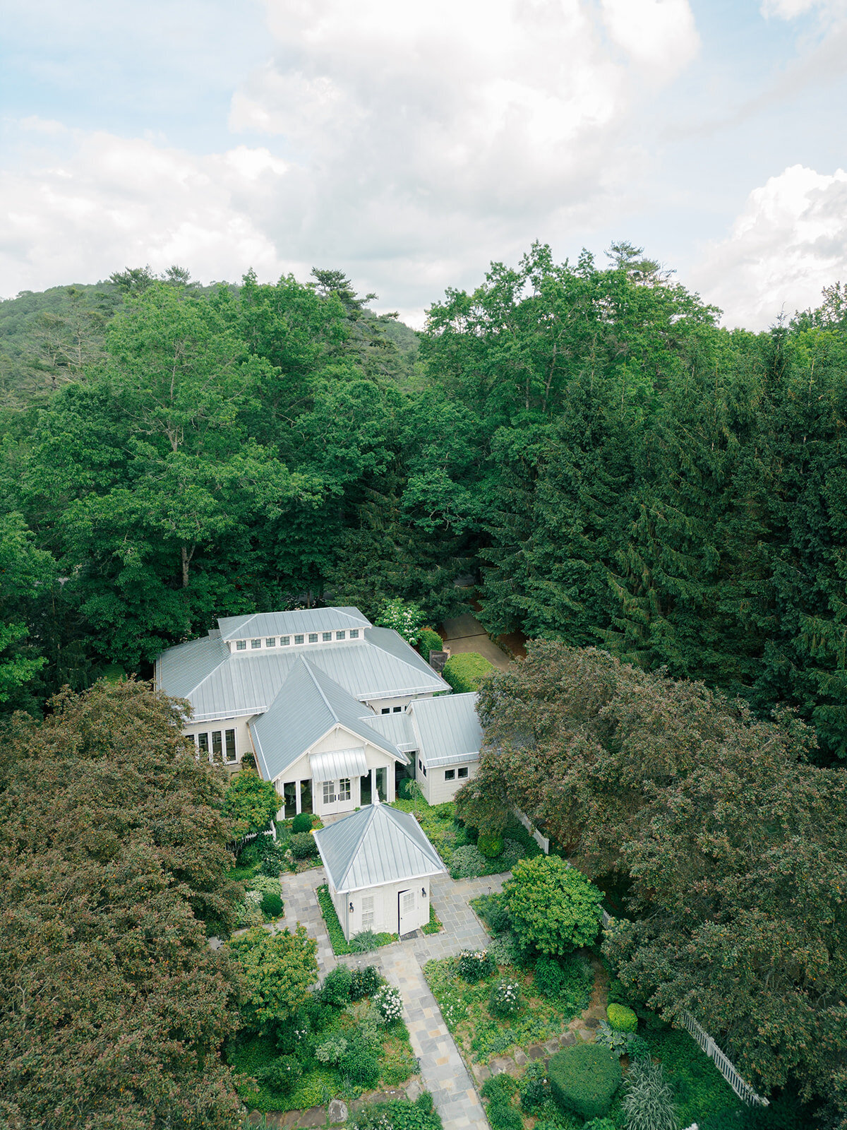 Aerial view of a private estate wedding venue surrounded by lush forest and mountain scenery in Highlands, North Carolina.