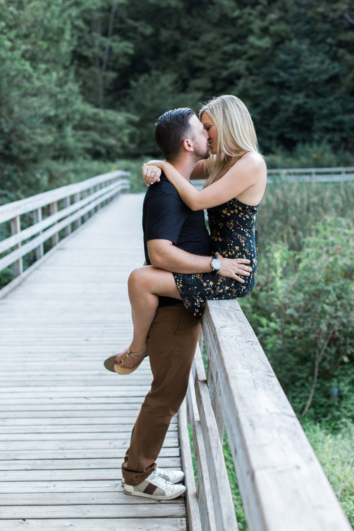 engaged couple kissing on a board walk