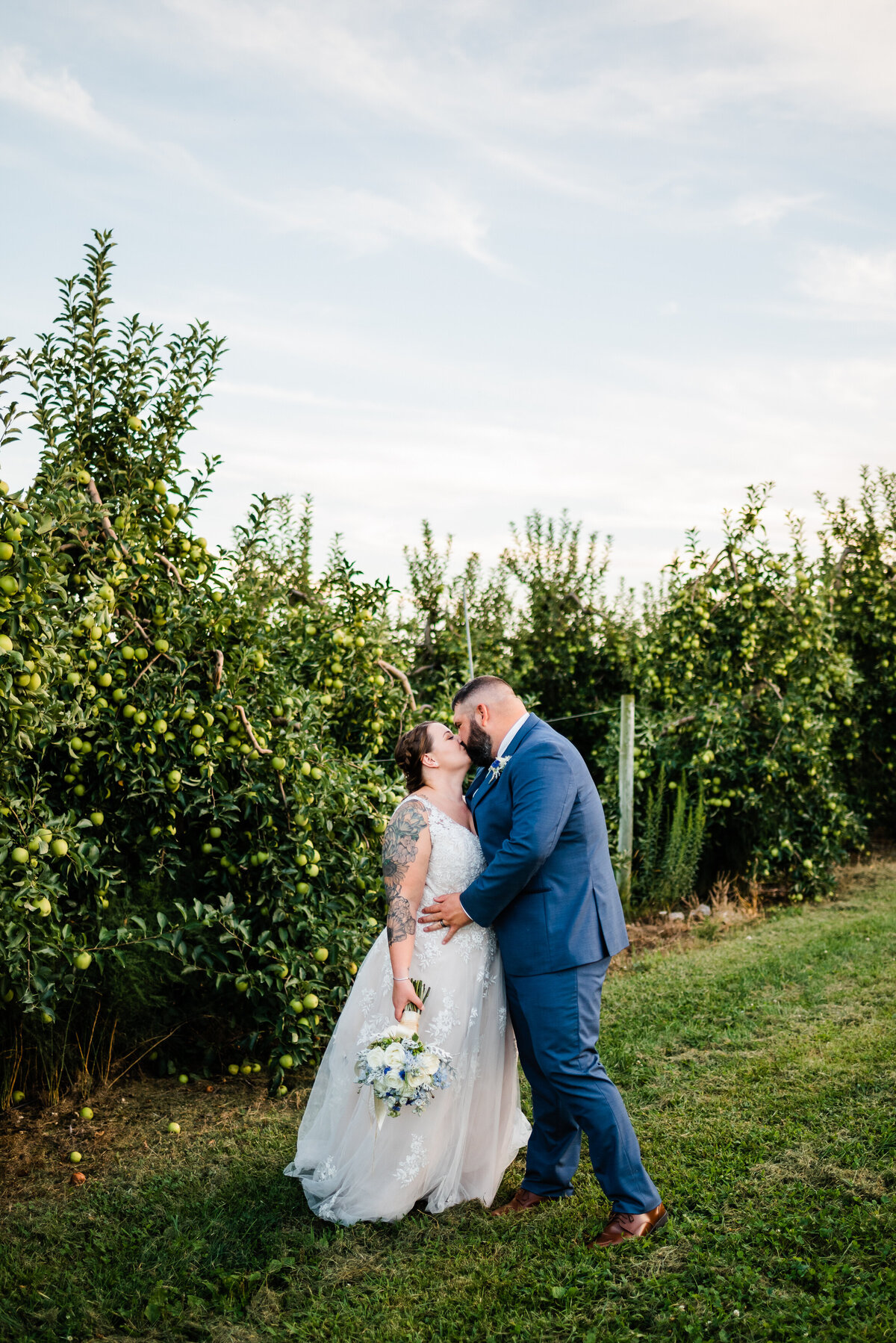 Shenandoah wedding at showalter's orchard greenhouse venue with bride and groom making out in the apple orchard for their spring wedding
