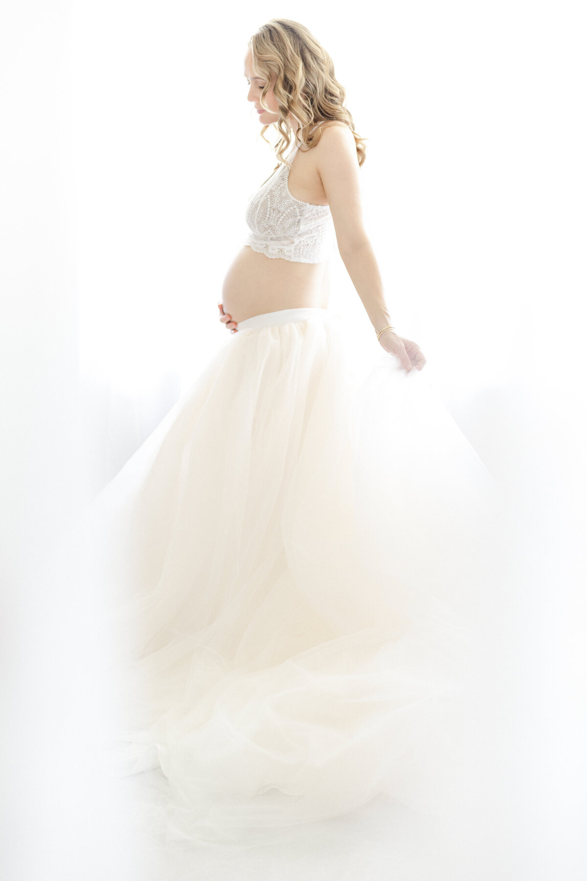 Elegant Tampa maternity portrait of expecting mother in flowing gown with soft studio lighting