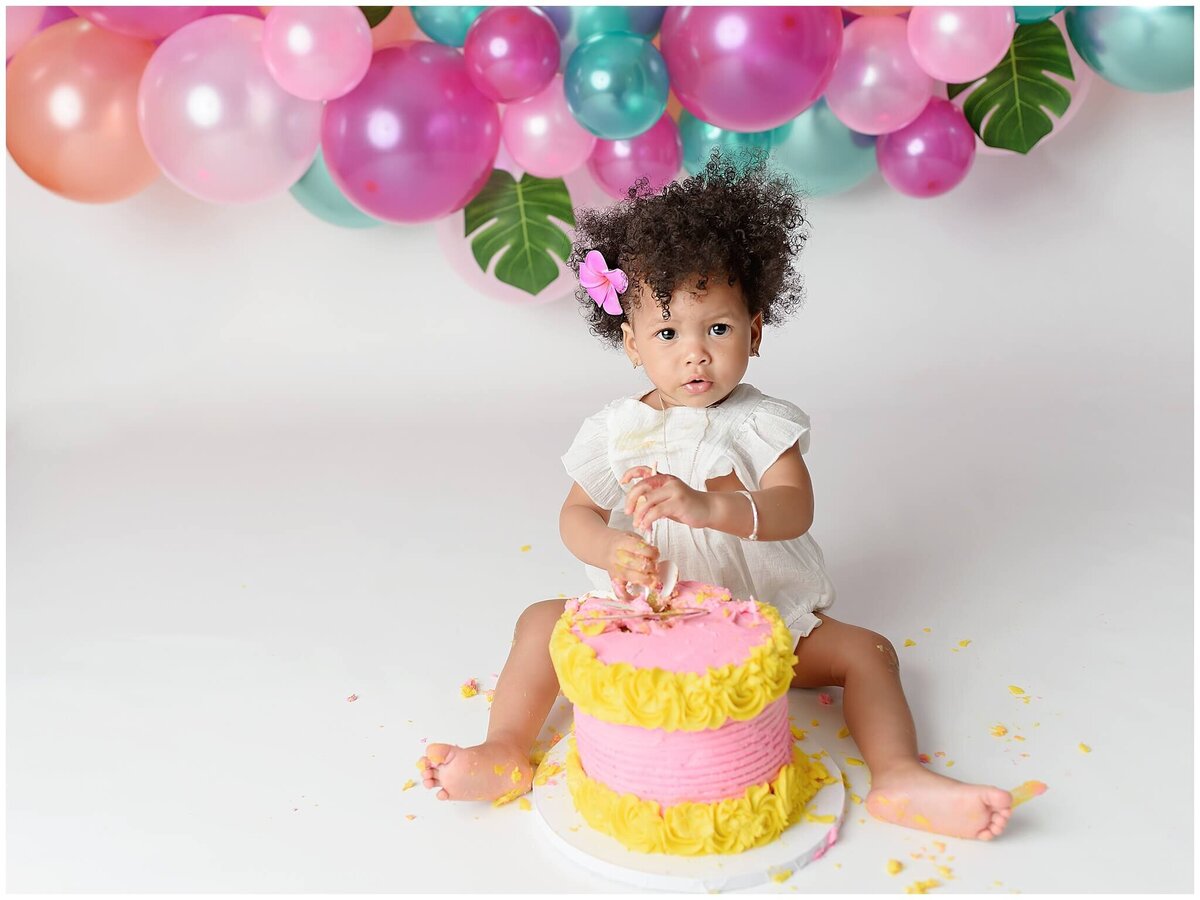 A little one exploring the textures and tastes of a cake during a fun-filled smash session.