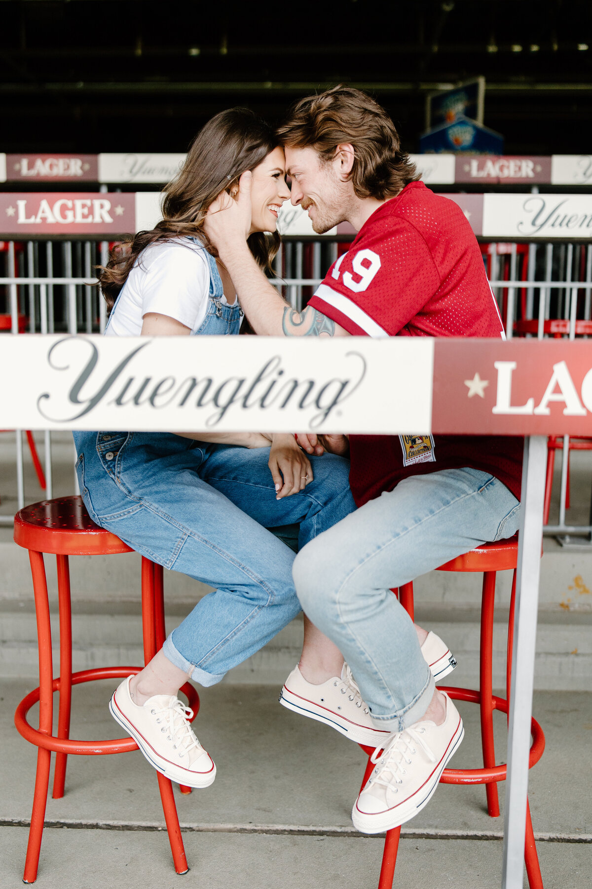 Couple sitting on bar stools in Yeungling section at Citizens Bank Park for baseball stadium engagement session