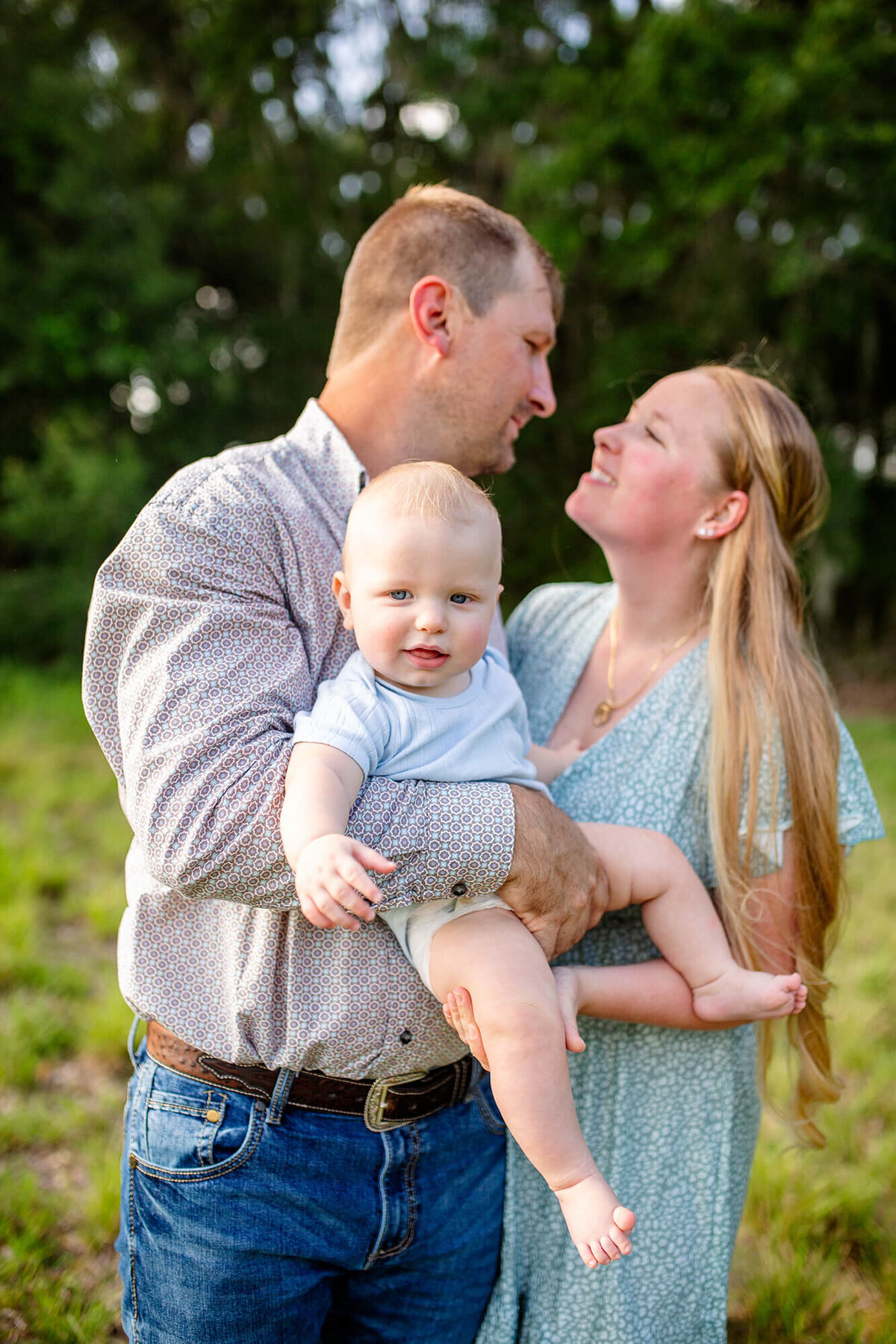Family portrait Session with mom and dad looking at each other and holding baby and smiling. Located at Jefferson Equestrian Park 
