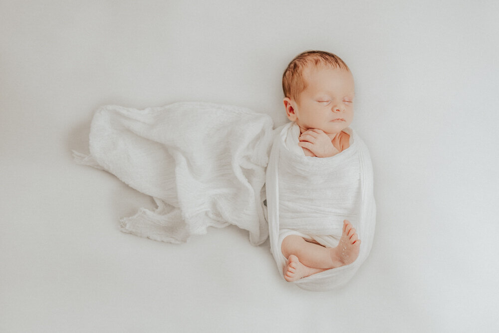 posed newborn baby wrapped in white wrap on white blanket - Townsville Newborn Photography by Jamie Simmons