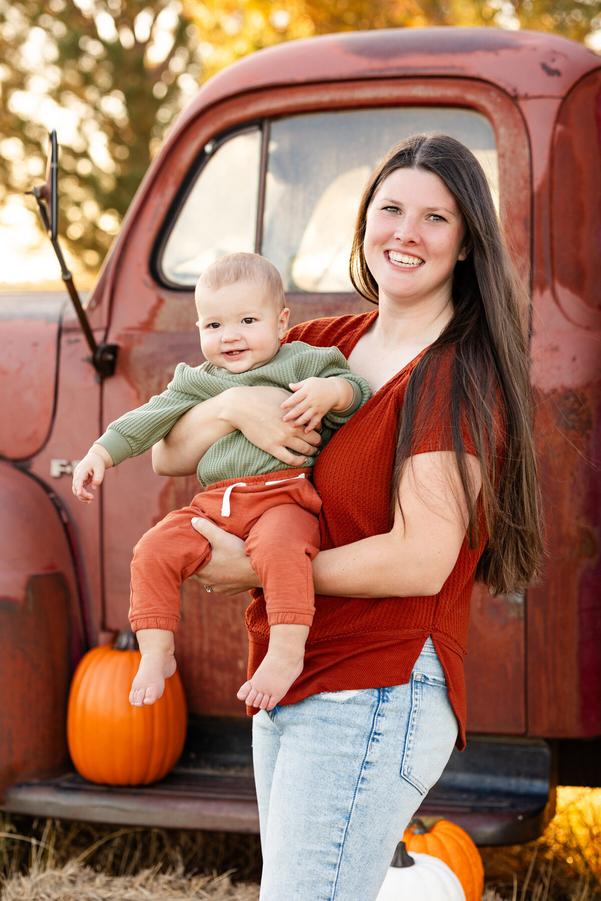 Mom holds baby boy and they both smile at the camera.