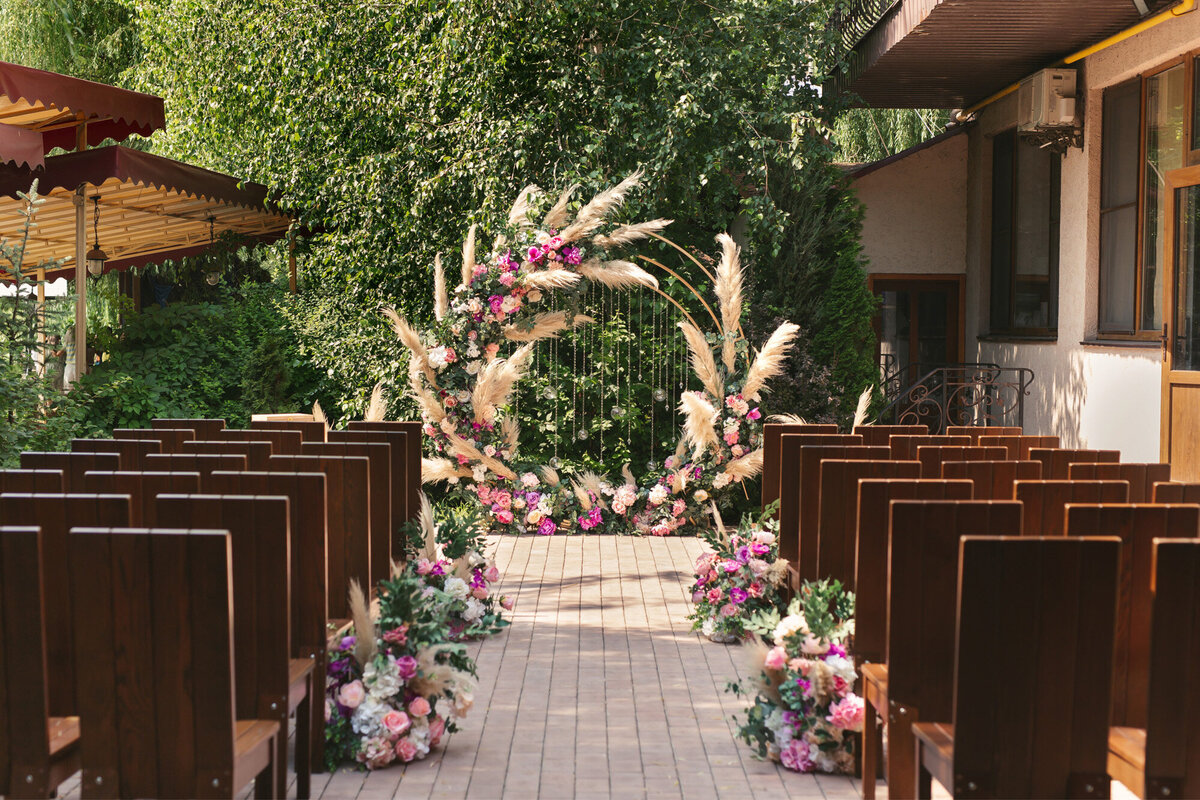 Outdoor wedding ceremony site with elegant florals and wooden chairs for guests