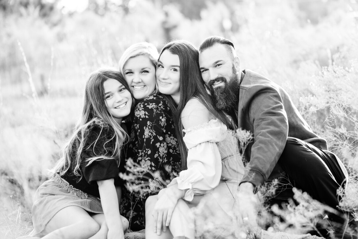 Family of 4 smiling at camera outdoors in black and white by Orlando Family Photographer