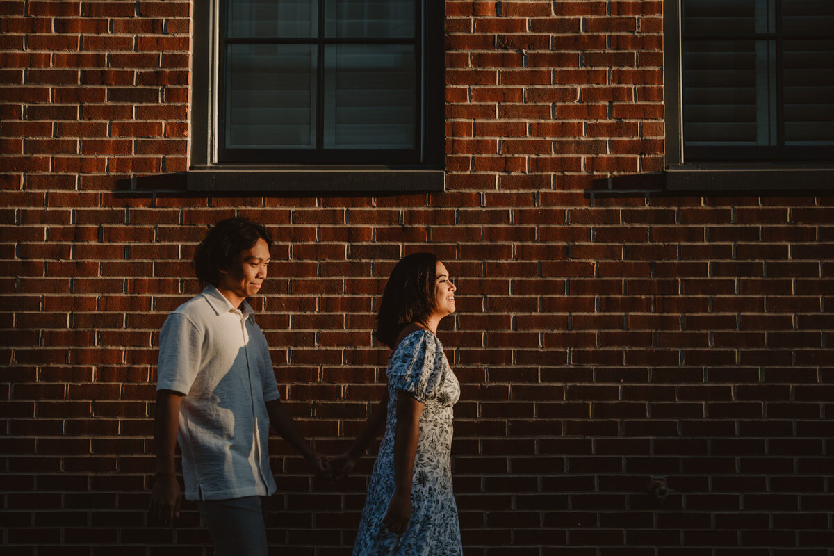 A couple walking one in front of the other and holding hands 