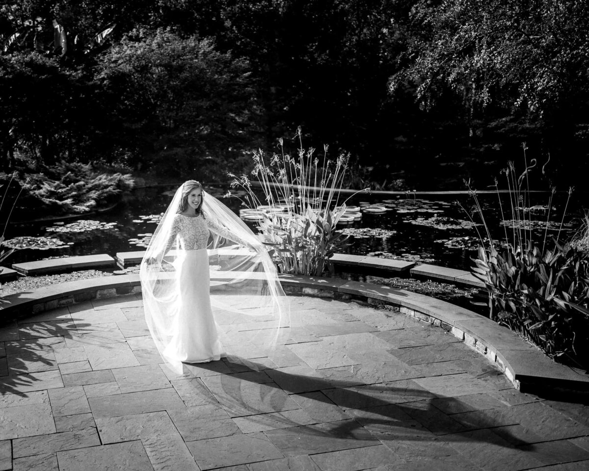 A bride holding out her veil while standing in a small patio area