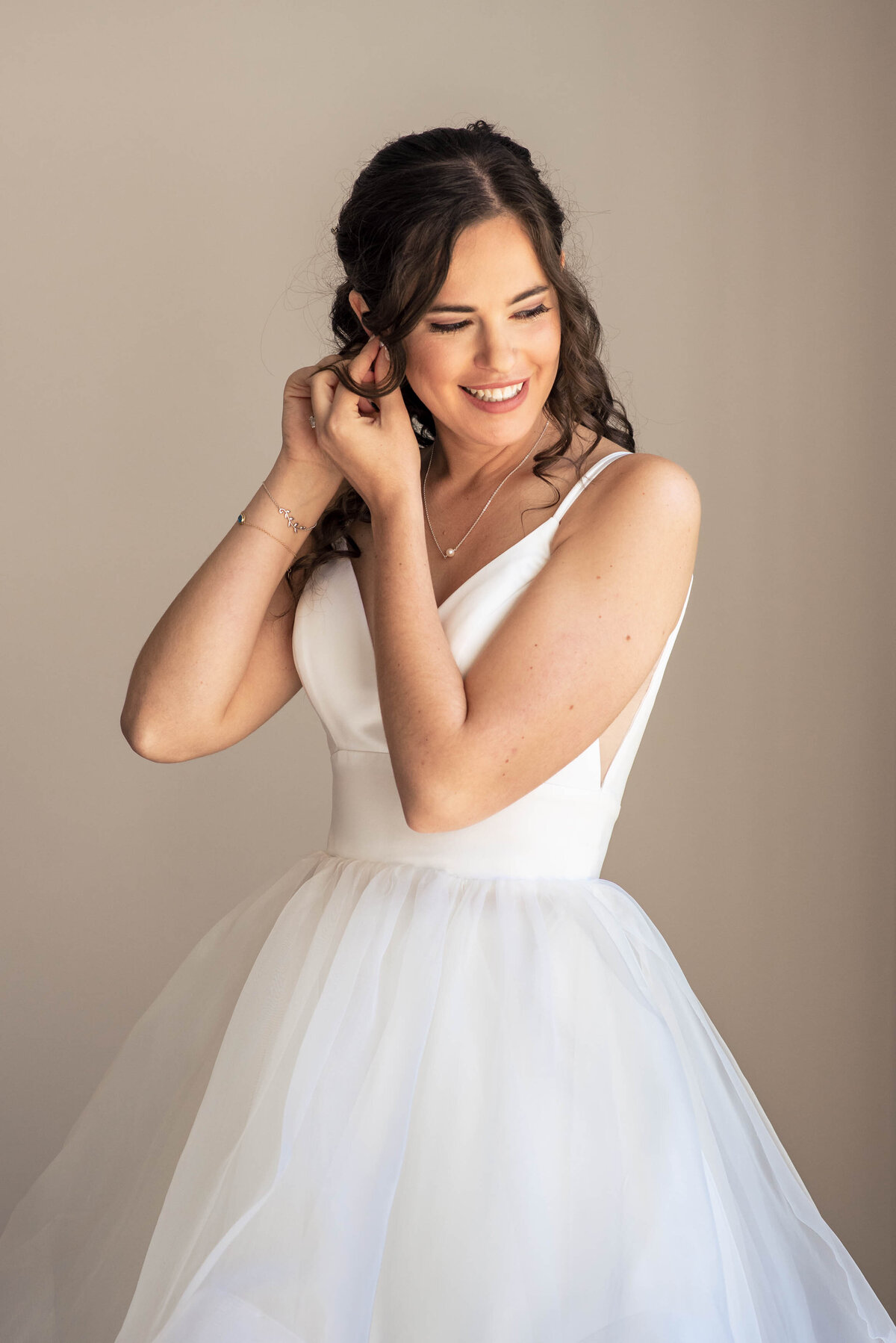 Bride in her white wedding dress looking down smiling while putting on her earrings getting ready for her wedding by Charlotte wedding photographers DeLong Photography