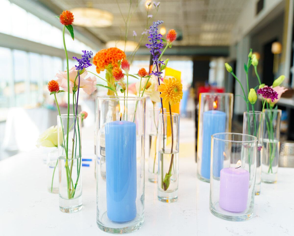 Blue and ourple candles with orange, yellow, and purple flowers on a white table at the North 4th Corridor (The Revery) in Columbus, Ohio.