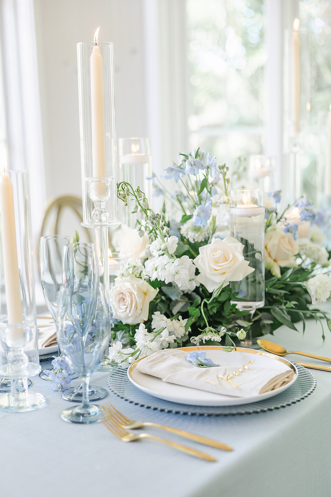 Blue and white florals with surrounded by candles. Blue and white table setting for a wedding dinner 