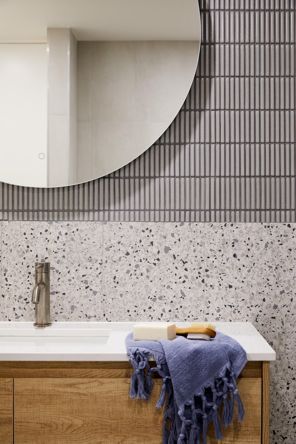 Close-up of Elwood apartment bathroom vanity with terrazzo splashback, round mirror and styled accessories