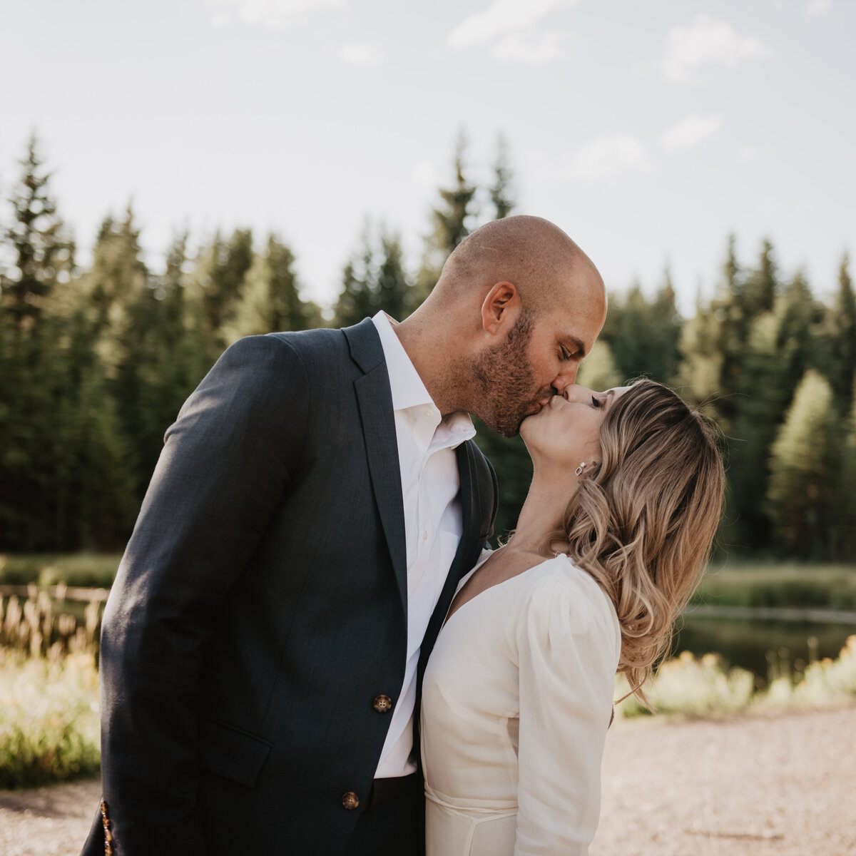 jackson wyoming photographer photographs jackson hole wedding with bride and groom elope in a forest and are kissing in front of a thick area of woods