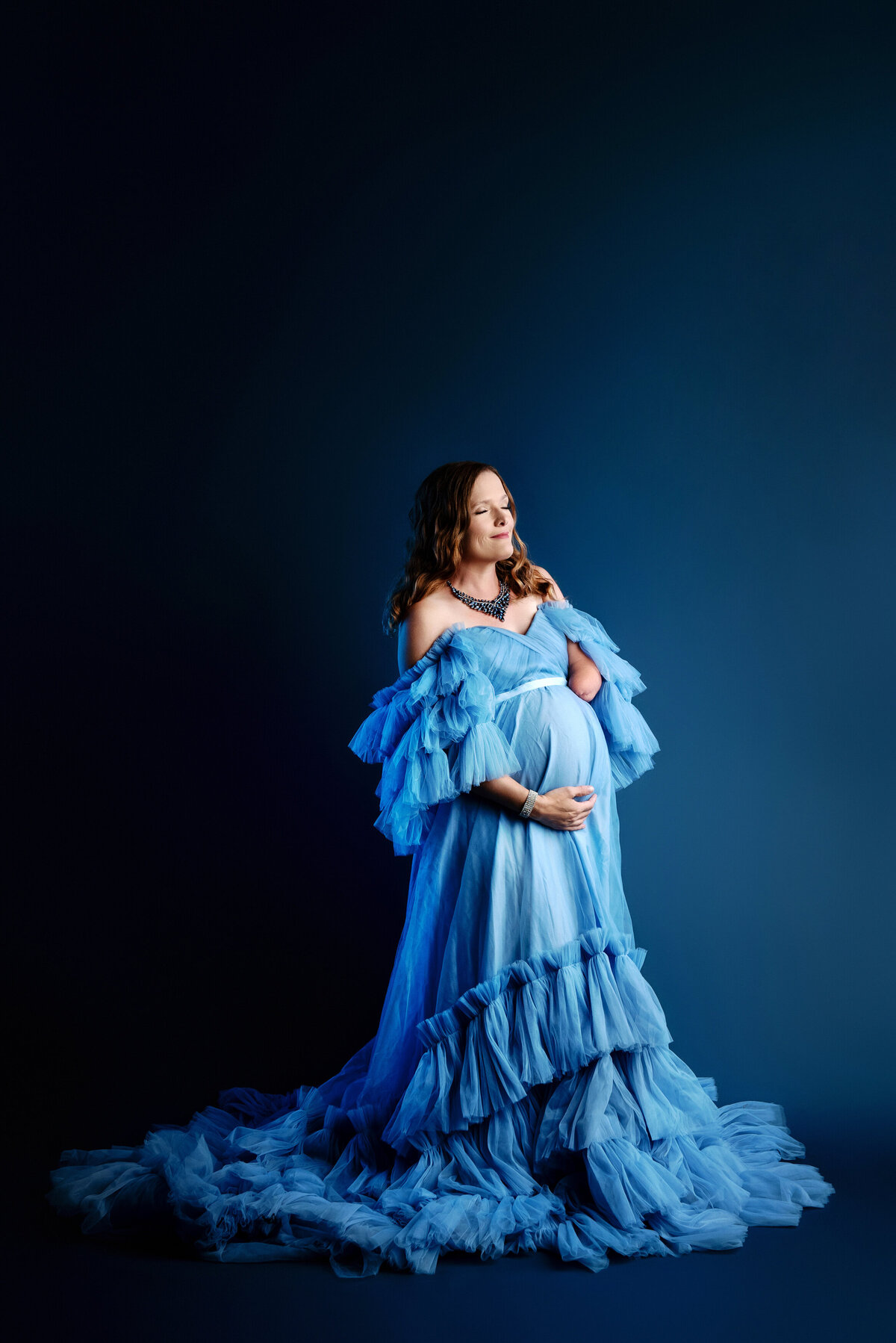 st-louis-maternity-photographer-mom-in-light-blue-tulle-gown-with-blue-backdrop-and-blue-lights