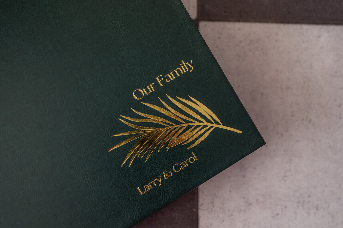 A green leather family album is embossed with gold lettering