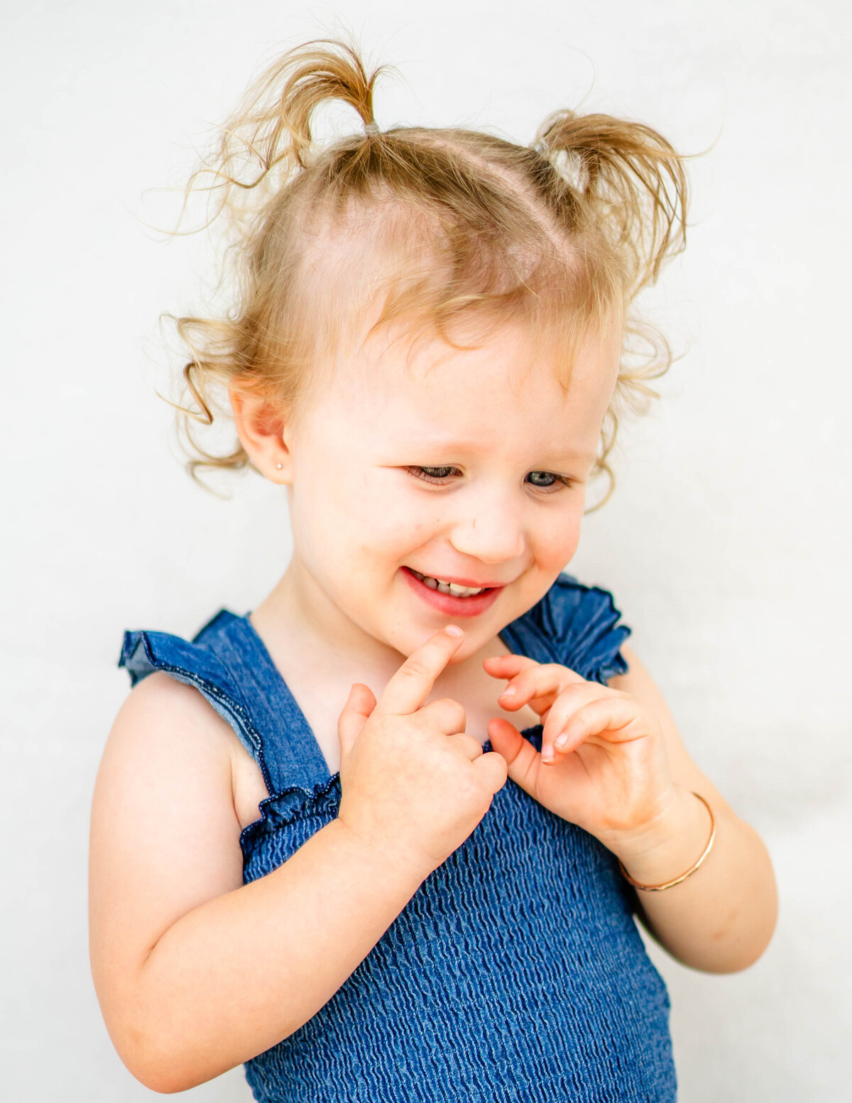Toddler girl smiling softly against a white backdrop — fine art school portrait by S. Reed Photography