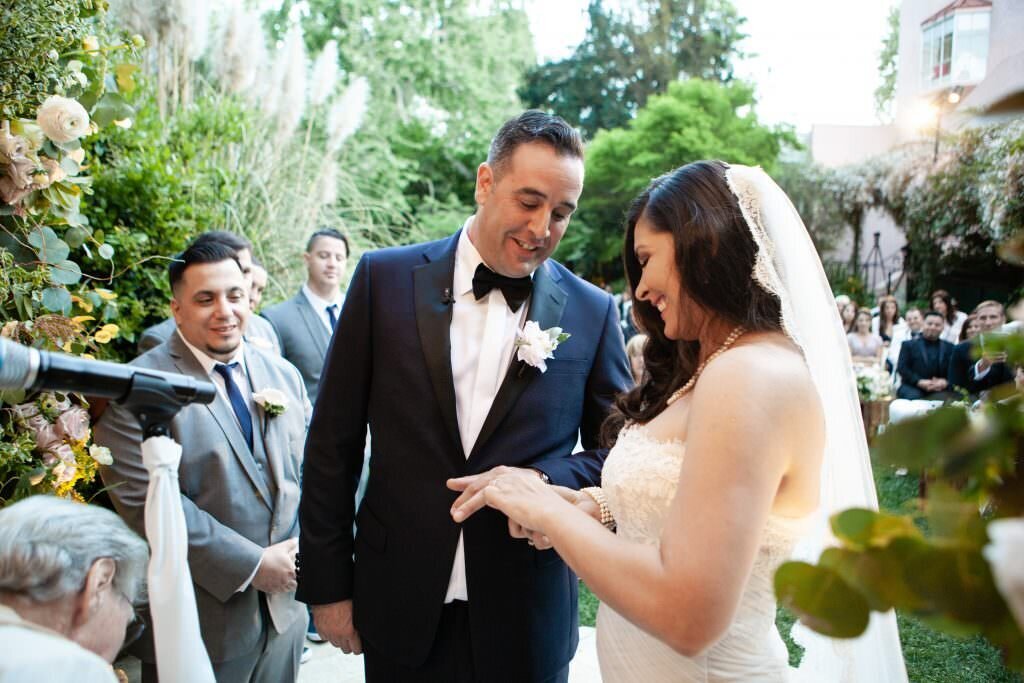 A bride and groom looking down at the ring on her finger