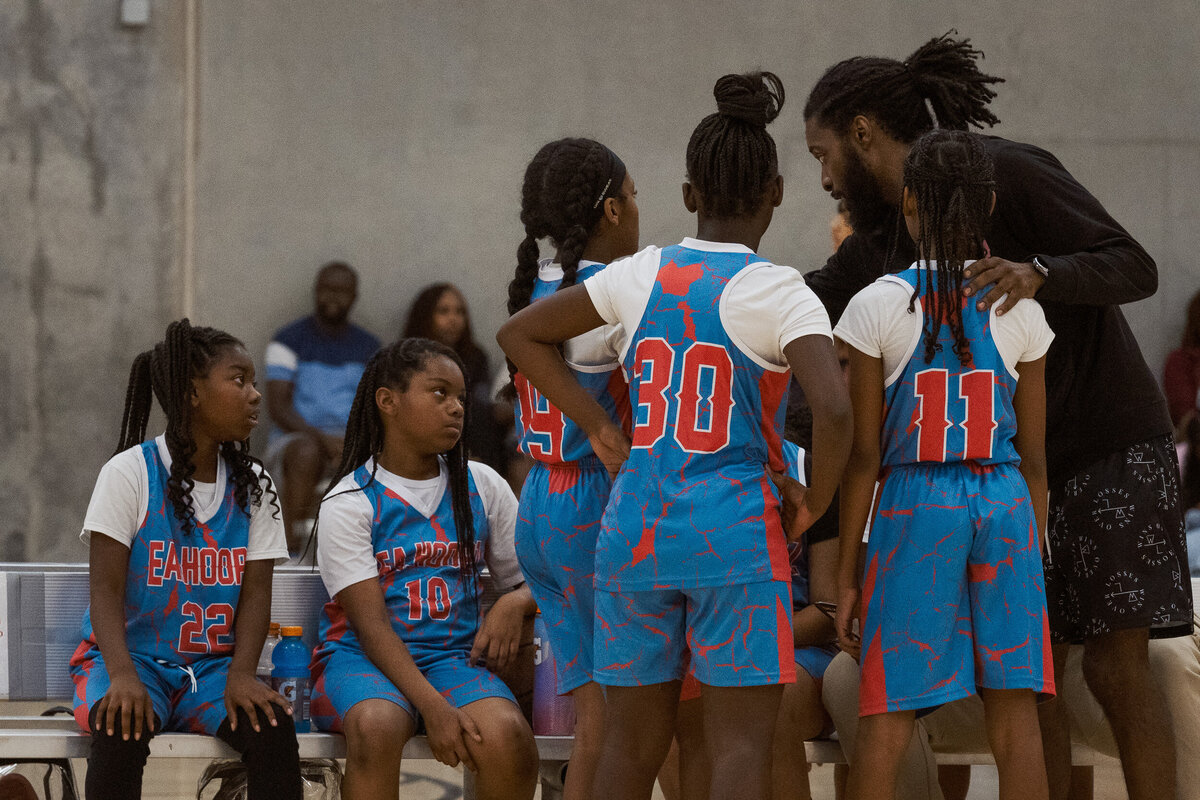 Full Circle Basketball TX girls basketball team huddling with their coach during a timeout in Fort Worth.
