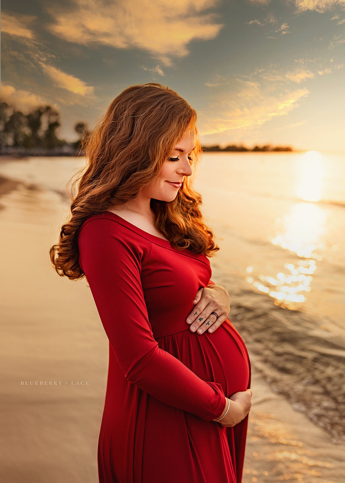 motherhood session outdoors on beach at sunset in red