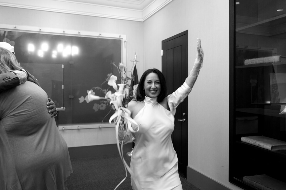 Bride Japna beams with joy, raising her bouquet in celebration after the City Hall wedding ceremony
