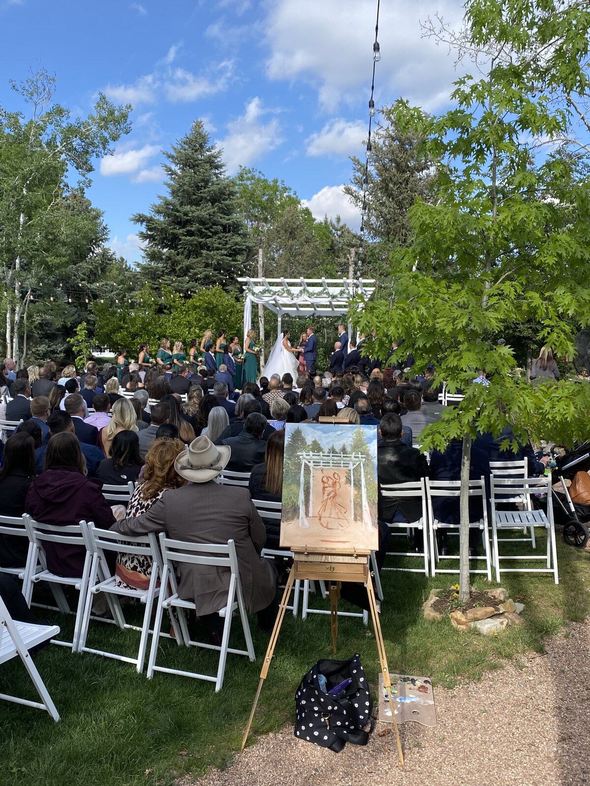 Denver's premier live wedding painter, Olivia Andruss, takes a snapshot of her easel and work in progress during the ceremony at Church Ranch Events Center