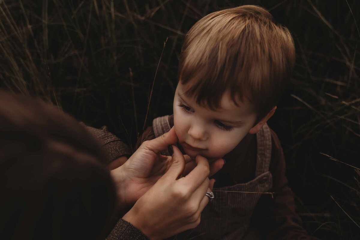 Mother wiping her son's mouth during a quiet moment at an outdoor session