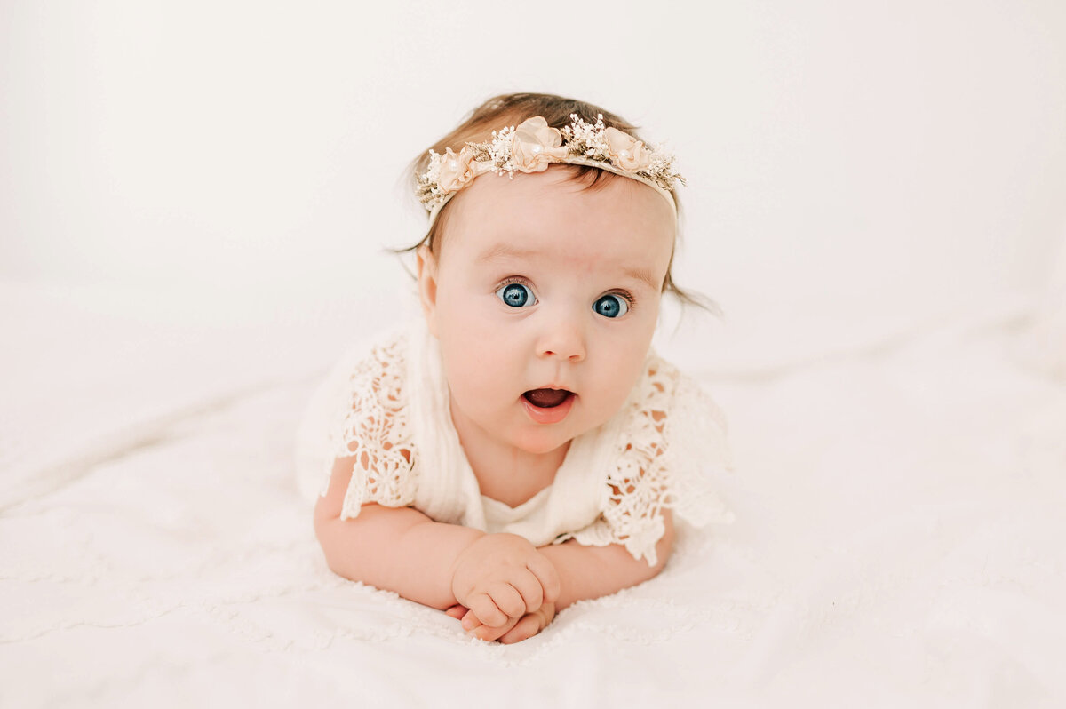 little girl in floral crown on bed in  Branson MO baby photography session