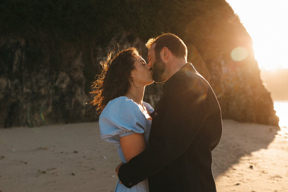 backlit with clever use of flare Photograph of a young  engaged couple at the beach in West Cornwall on a sunny day