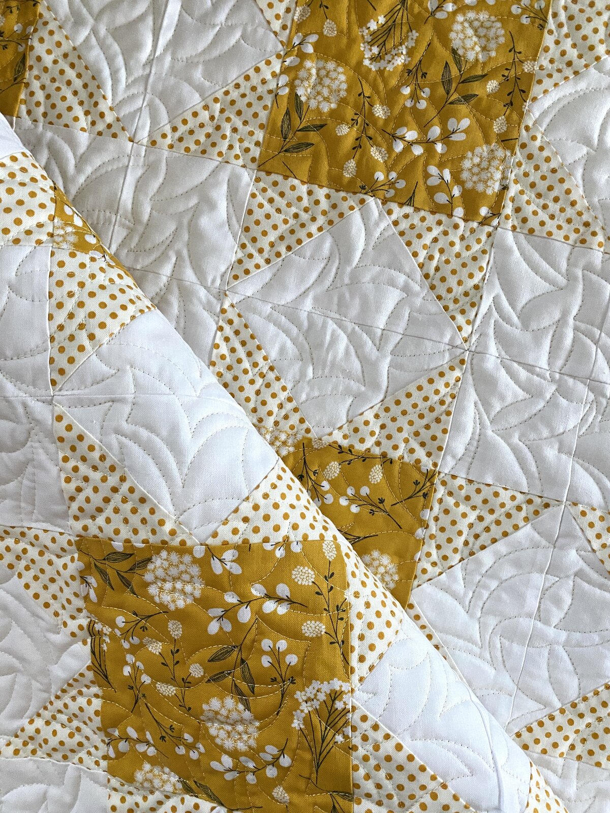 the boomerang quilting design on a gold and white quilt