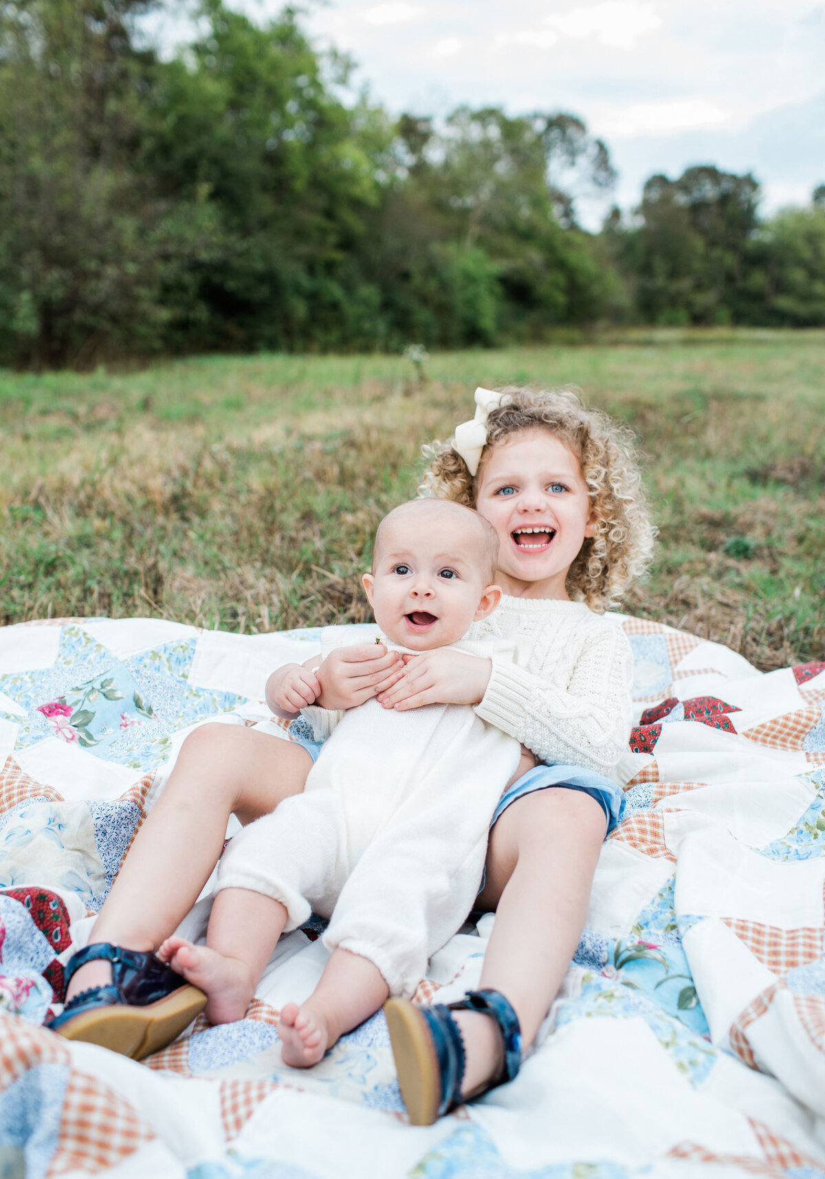 two small kids sitting on a blanket in a field in Chattanooga