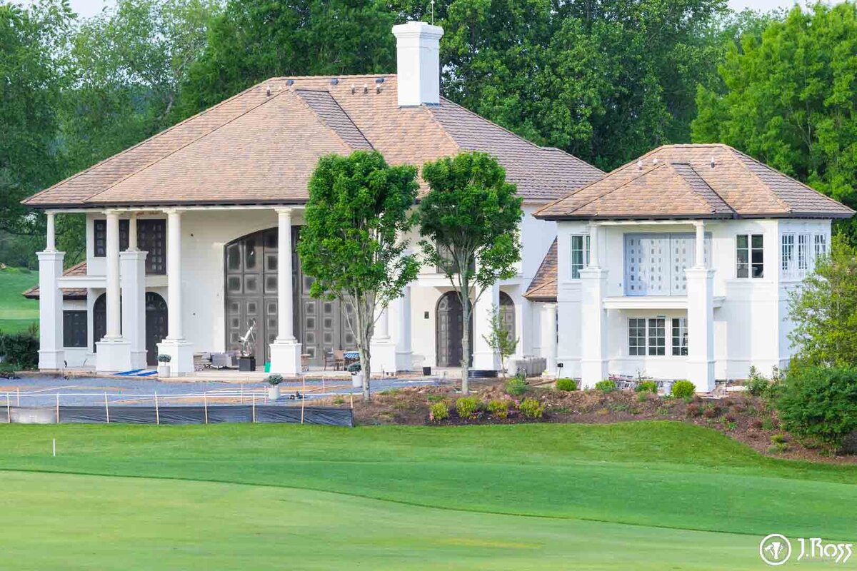 View of the main house and secondary structure from the golf course, highlighting the extensive professional work involved in this detailed home exterior painting Bristol, VA restoration.