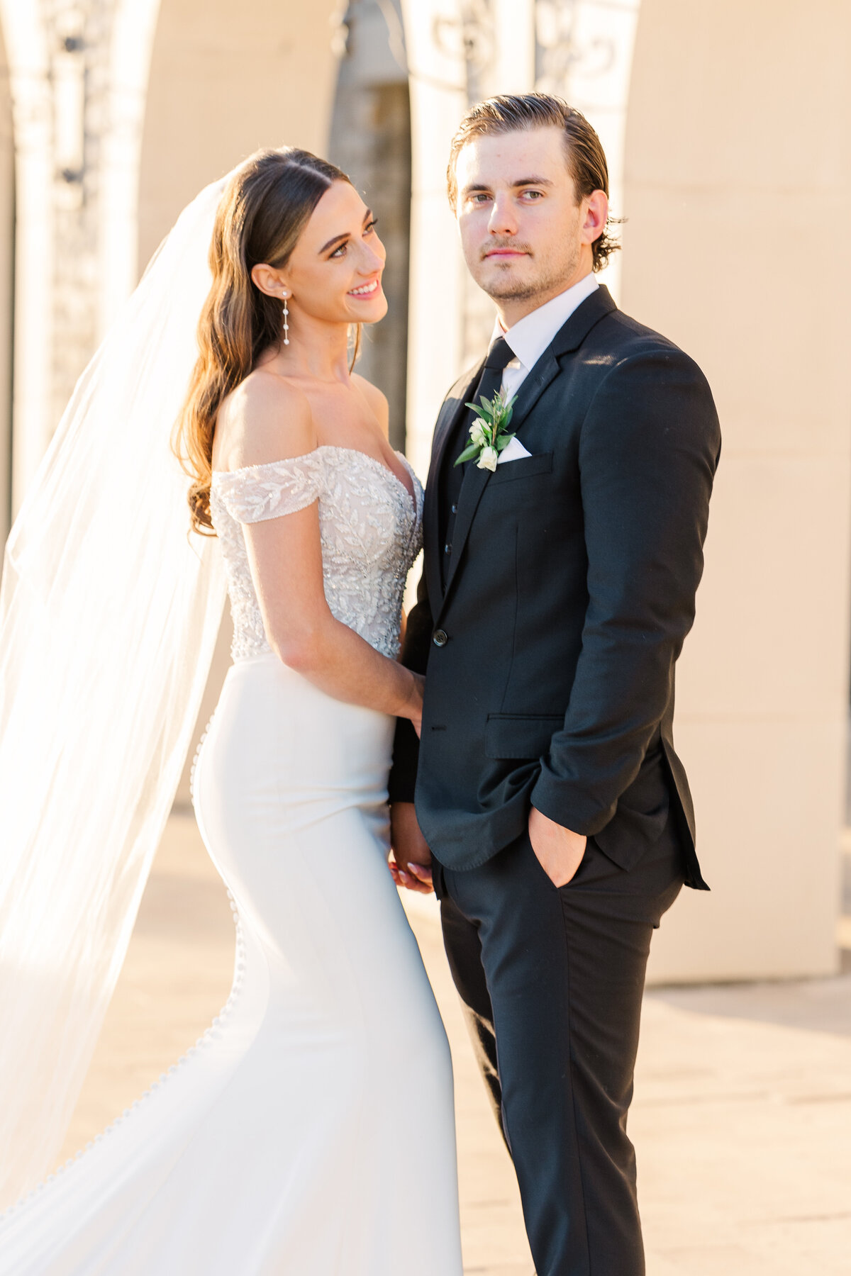 A romantic moment as the groom kisses his bride on the temple, framed by rustic stone architecture. Taken in Westlake, TX, near the Dallas-Fort Worth area.