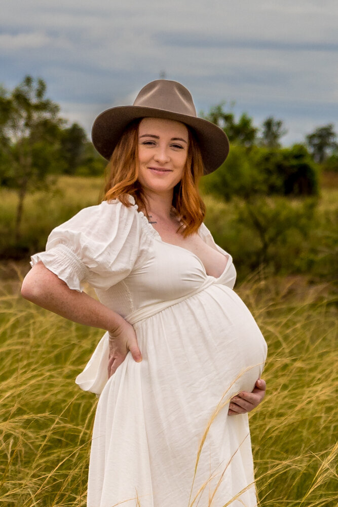 pregnant woman in white maternity gown holding baby belly - Townsville Maternity Photography by Jamie Simmons