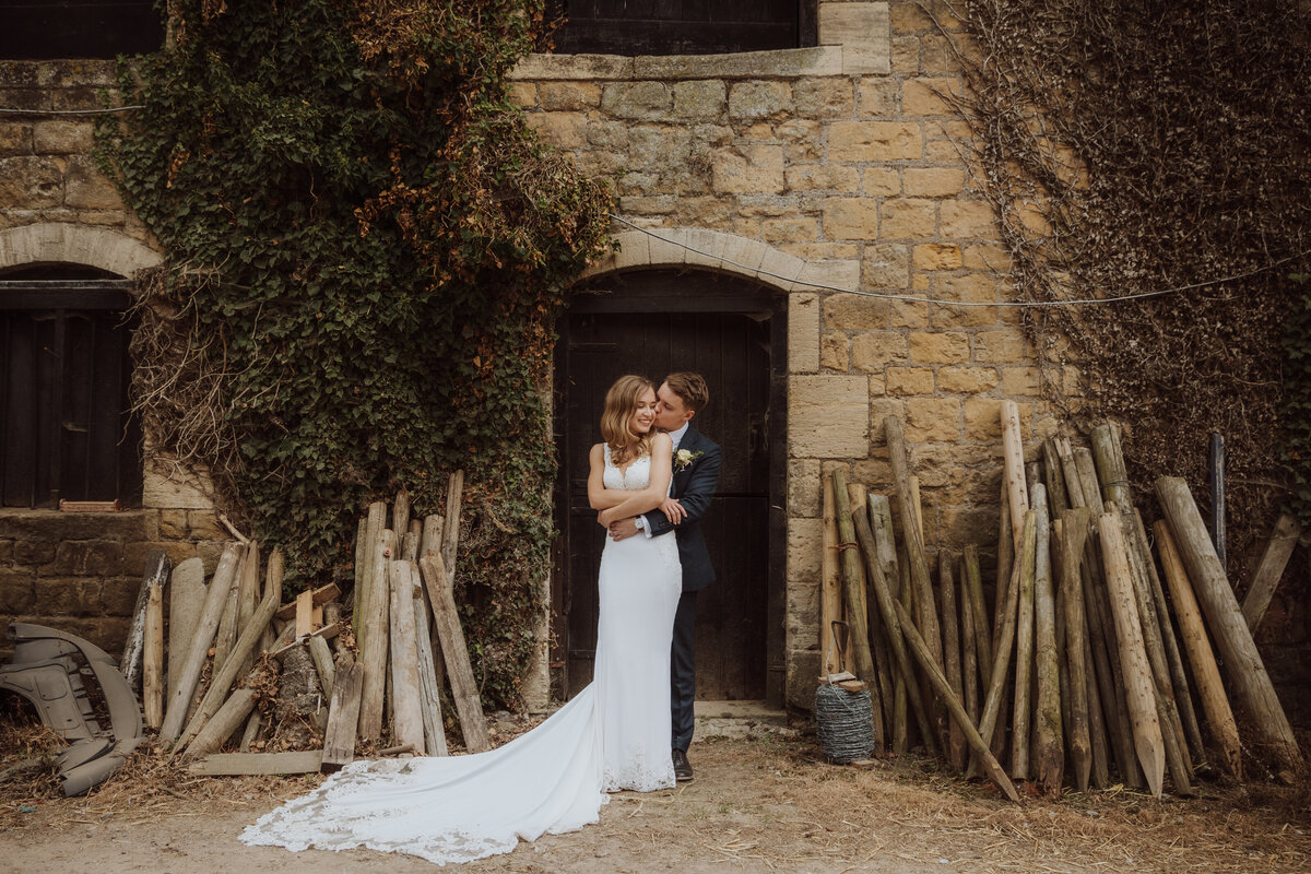 A bride and groom stood against a rustic barn