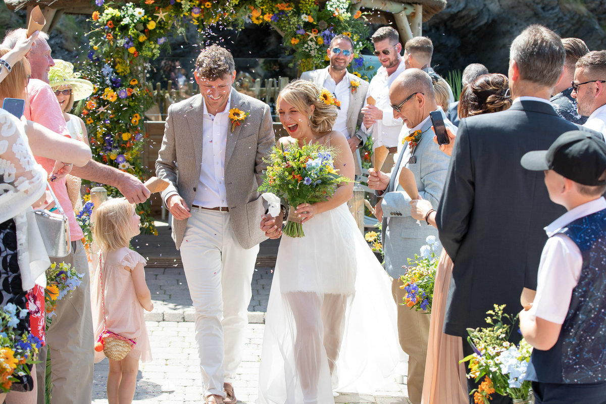 Confetti walking down the aisle Tunnels Beaches wedding venue in Devon