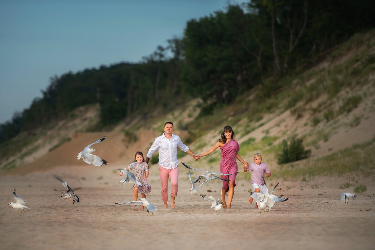 family of four having fun chasing seagulls at the Indiana dunes beach by lake Michigan