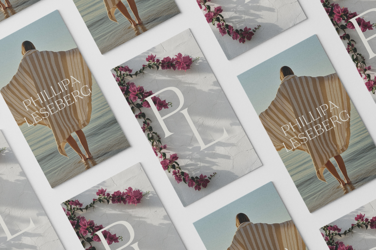 A flat lay of cards featuring a woman in a striped cover-up by the water, with "PL" initials, pink flowers, and "PHILLIPA LÆSEBERG." A charming showcase of Brand Design by Sweet Pea Ink Creative.
