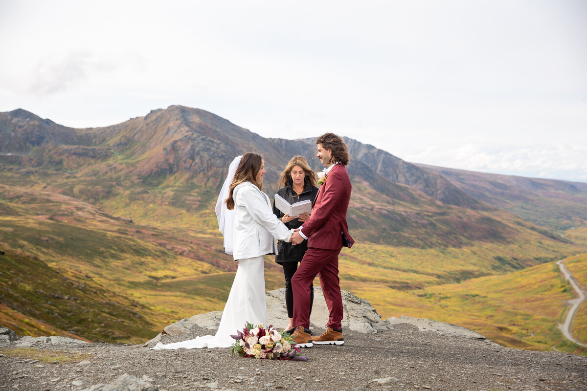 An officiant reads a script as a bride and groom stand holding hands.