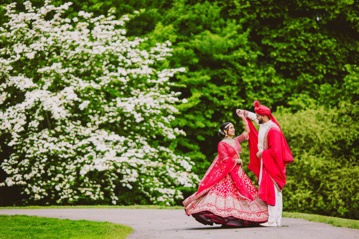 Groom twirling bride at their Indian wedding at the Frelinghuysen Arboretum in New Jersey