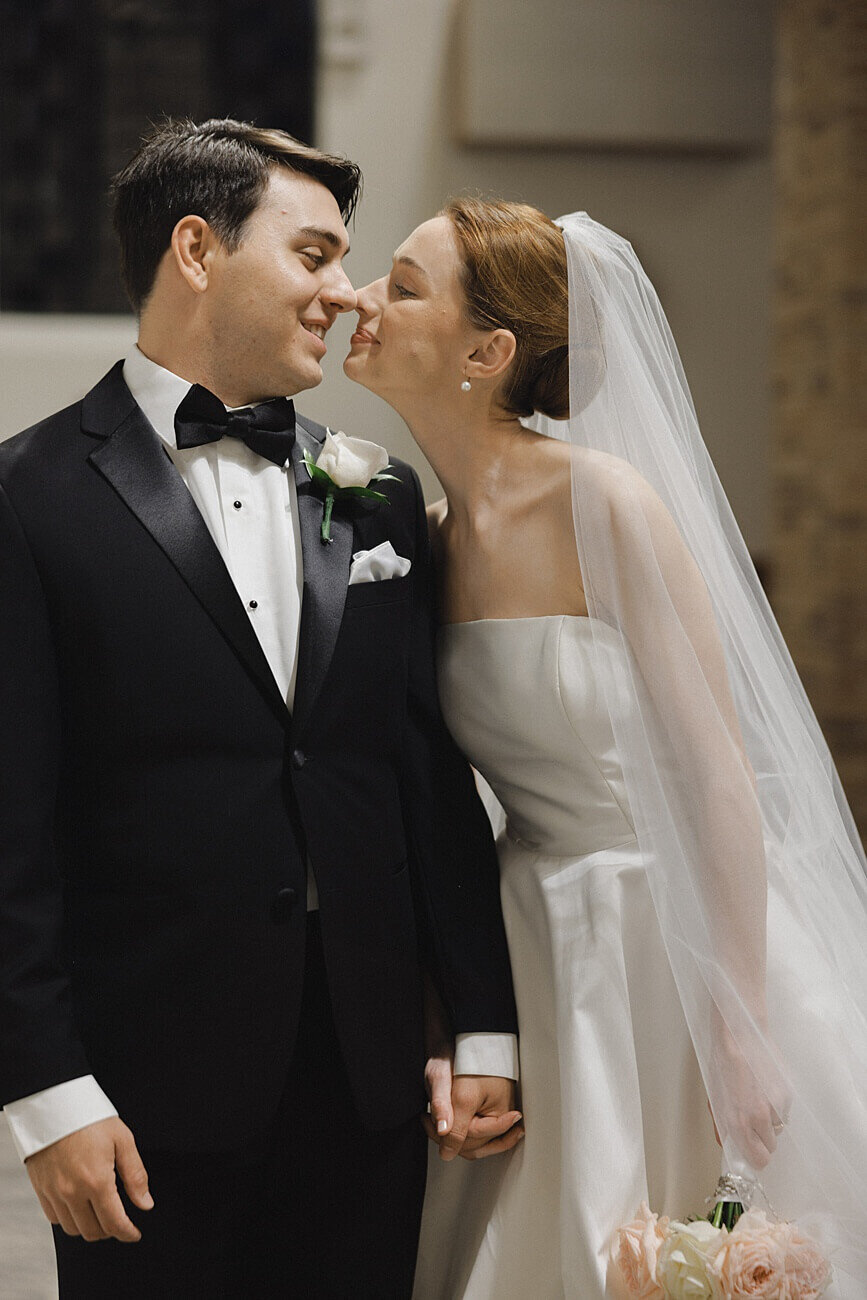 bride and groom rub noses together in church