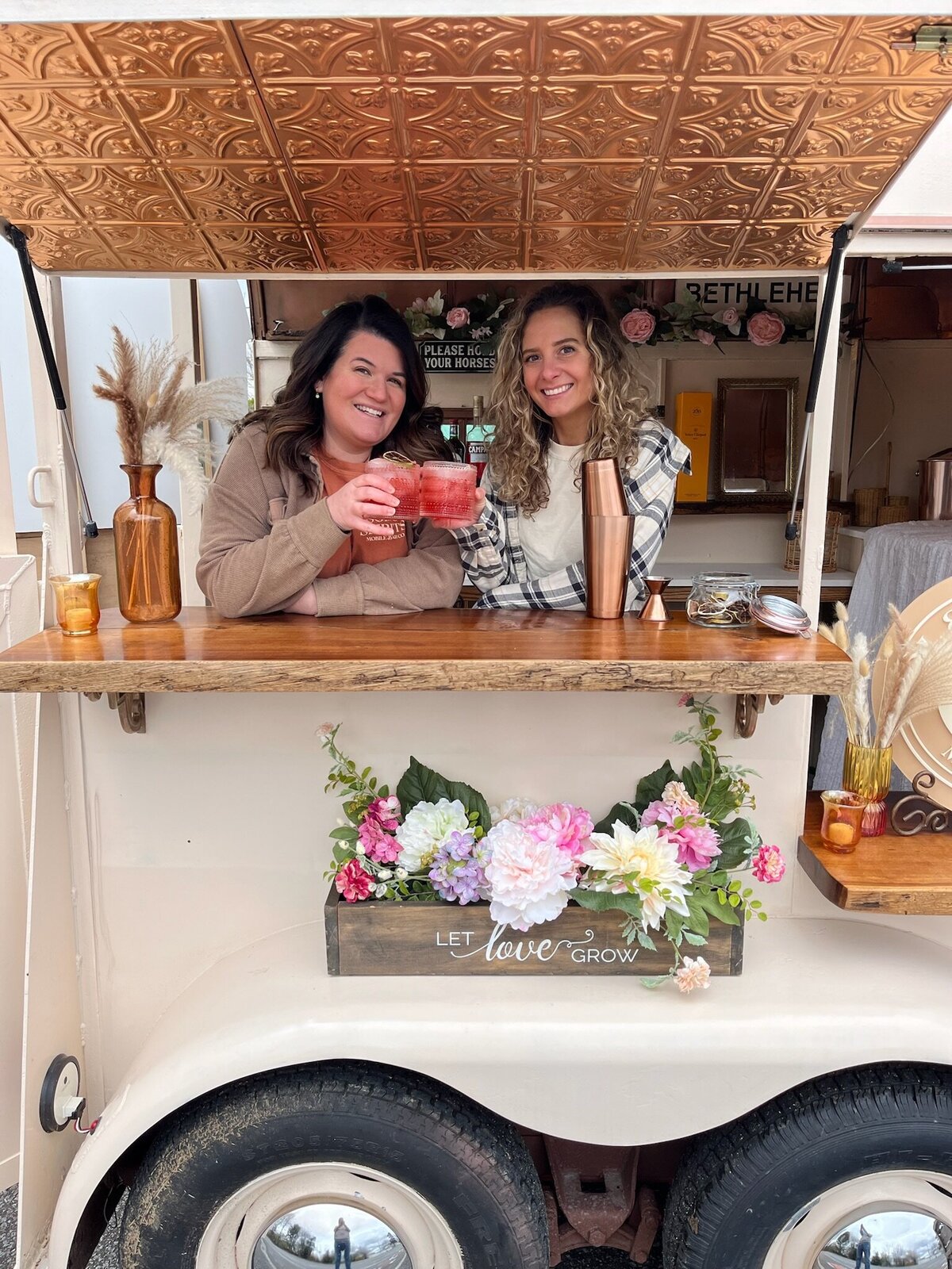 Owners pose in horse trailer bar with cocktails