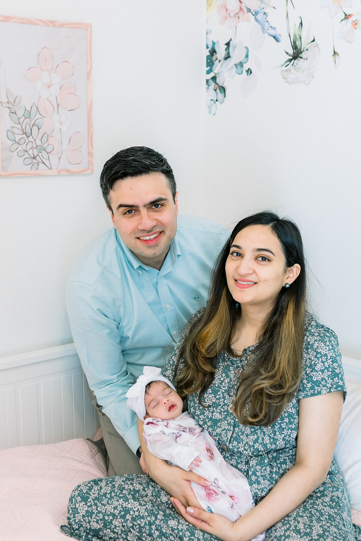 Black and white lifestyle newborn photography featuring a loving couple holding their sleeping baby girl. This intimate family moment highlights the joy of welcoming a newborn at home
