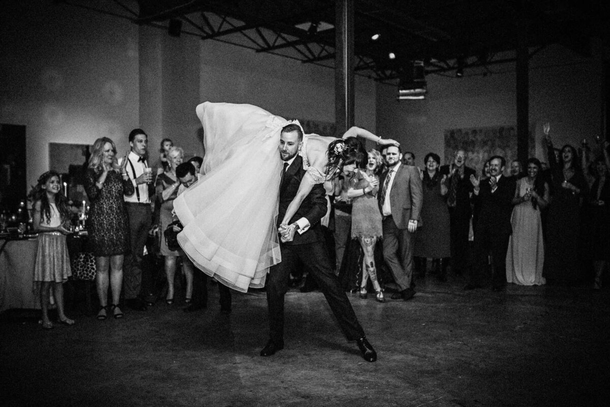 A groom lifting his bride on his shoulder as they dance.