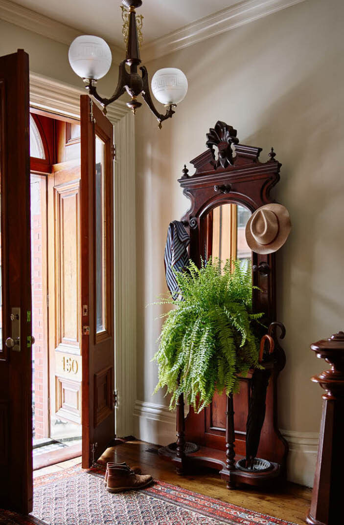 The foyer features a 125-year-old light fixture, vintage hall tree, and original doors, trim, and flooring. A true nod to Boston's rich history. By Sarah Scales.